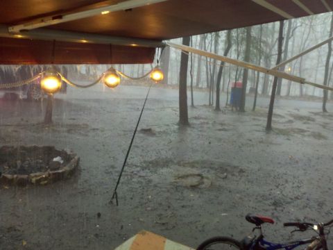 1995 Ford Bronco - A campsite scene during a rainstorm, with a bicycle visible in the foreground under an awning.