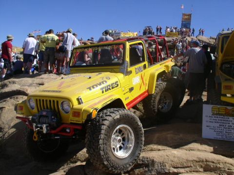 1979 Ford Bronco - A modified Jeep Wrangler navigates a rocky obstacle course with spectators gathered on the hillside.