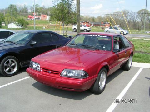 2007 Ford Mustang - Front three-quarter view of a red Fox-body Ford Mustang LX hatchback with clear-lens headlights, smooth front bumper and white five-spoke P…
