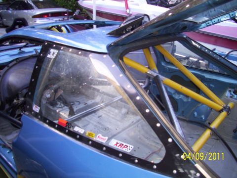1995 Ford Probe - The interior of a modified blue car shows a yellow roll cage and racing seat, with stickers on the window frame.
