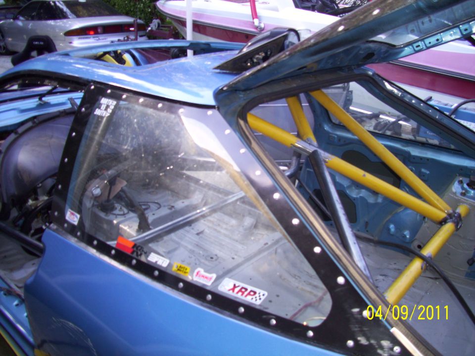 Blue race car interior, yellow roll cage, racing seat, stickers on window frame, dated 04/09/2011