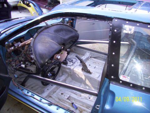 1995 Ford Probe - The interior of a car has been stripped down and fitted with a roll cage, revealing exposed wiring and a bare chassis.
