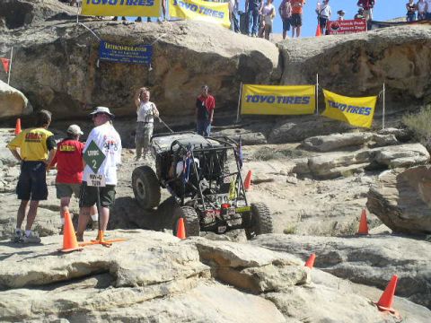 1979 Ford Bronco - An off-road buggy navigates a rocky course, marked by orange cones and sponsored by Toyo Tires.