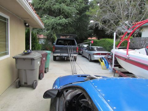 1995 Ford Probe - A blue sports car's interior and hood are in the foreground, with a truck, sedan, and boat behind it.