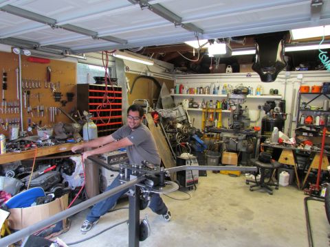 1995 Ford Probe - A man uses a metal bending tool in a workshop filled with various tools and equipment.