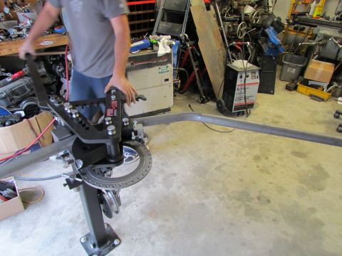 1995 Ford Probe - A metal pipe is being shaped using a tube bending machine in a cluttered workshop environment.