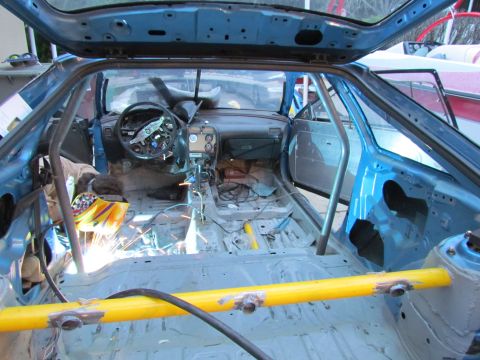 1995 Ford Probe - Custom roll cage installation in a 1995 Ford Probe interior, with welding sparks visible.