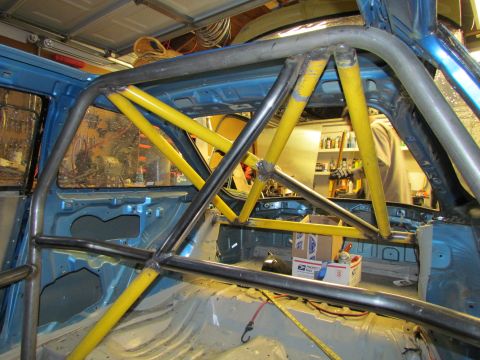 1995 Ford Probe - The interior of a blue vehicle is heavily modified with a custom roll cage.