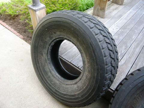 1986 Ford Bronco - A single BFGoodrich tire rests on a weathered wooden deck next to a concrete path.