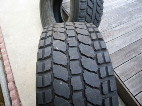 1986 Ford Bronco - Two off-road tires are shown resting on a wooden deck.