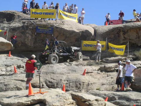 1979 Ford Bronco - An off-road buggy navigates a rocky course with spectators watching from above.
