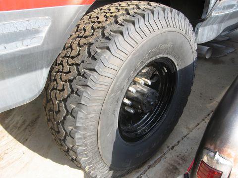 1986 Ford Bronco - Close-up of a tire and wheel assembly on a red vehicle, showing BFGoodrich All-Terrain T/A tires.