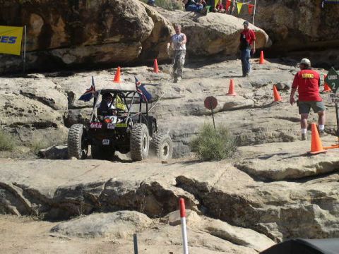 1979 Ford Bronco - An off-road buggy with flags navigates a challenging rocky course during an event.