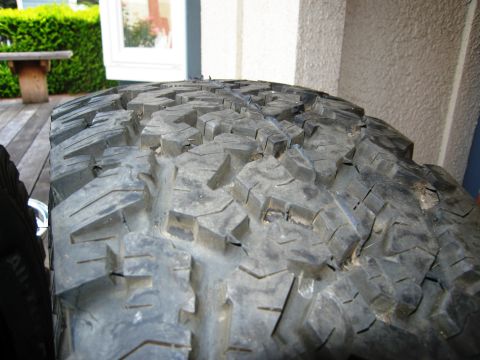 1986 Ford Bronco - A close-up view of a BFGoodrich All-Terrain tire shows its deep tread blocks and sidewall details.