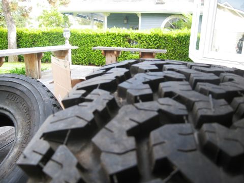 1986 Ford Bronco - Close-up of a BFGoodrich tire tread, with a house and yard visible in the background.