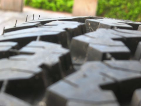 1986 Ford Bronco - A close-up view of a tire's tread pattern, showing its aggressive design and some small protruding spikes.
