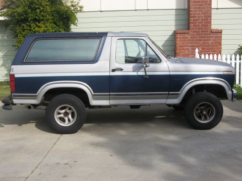 1986 Ford Bronco - Two-tone blue and silver 1986 Ford Bronco parked on a concrete driveway.