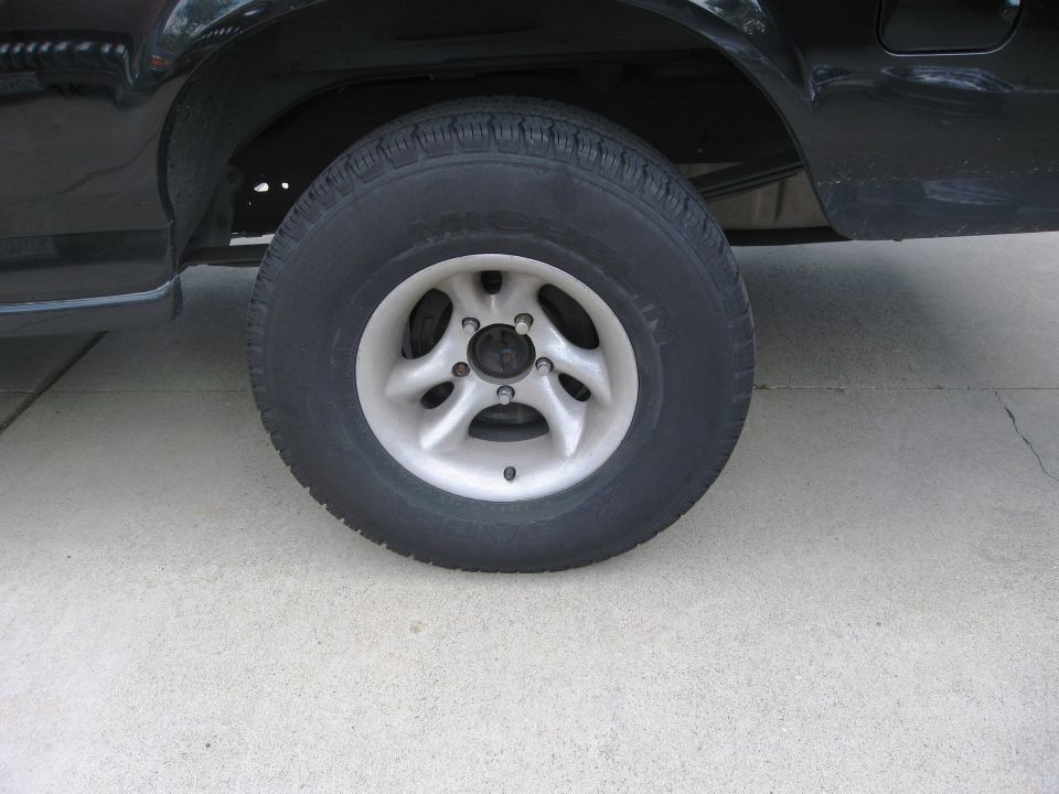 Black vehicle rear wheel and tire on concrete