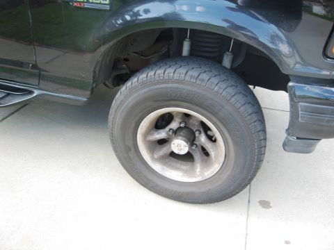 1986 Ford Bronco - Close-up of the front wheel and fender of a black Ford Bronco XLT.