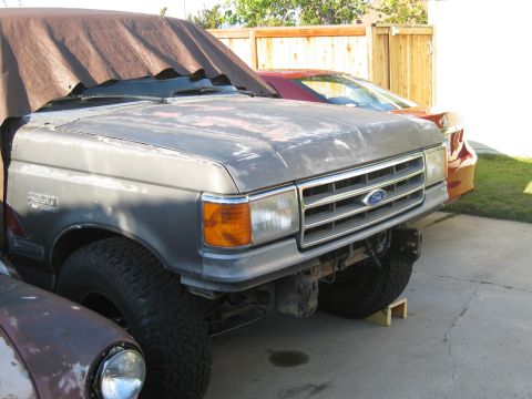 1986 Ford Bronco - Front view of a 1987 Ford F-Series truck, partially covered by a tarp.