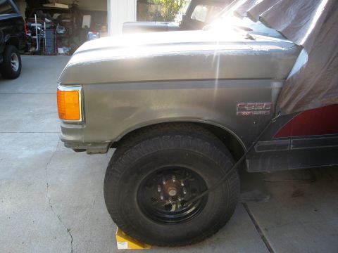 1986 Ford Bronco - Front clip of a 1987 Ford F-Series truck, showing the fender, wheel, and a partial view of another vehicle in the background.