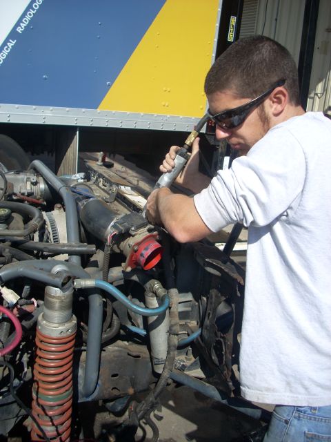 1992 Ford Ranger - Mechanic performs maintenance on a complex engine assembly, surrounded by tools and vehicle parts.