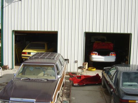 1984 Ford Mustang - A 1984 Ford Mustang is visible in a garage, alongside other vehicles and car parts.