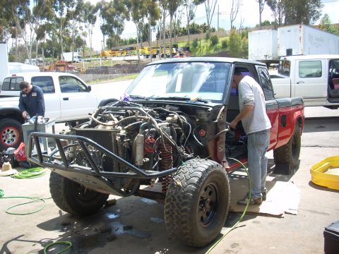 1992 Ford Ranger - Mechanics work on a red pickup truck that has had its front end removed, revealing the engine and suspension components.