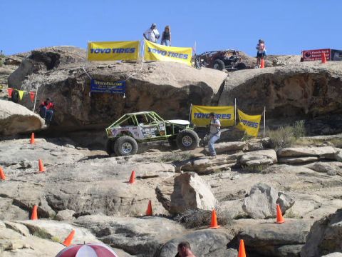 1979 Ford Bronco - A custom off-road buggy tackles a challenging rock climb course with spectators watching.