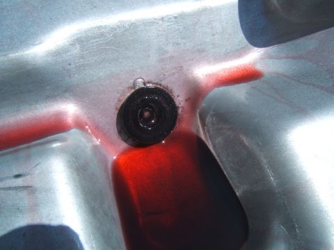 1988 Ford Bronco - Transmission pan shows red fluid pooling around the drain plug, indicating a potential leak or recent service.