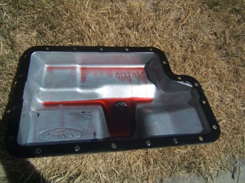 1988 Ford Bronco - A Ford transmission pan, likely from an E4OD transmission, shows red fluid and metal debris.