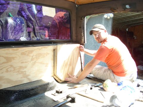 1992 Ford C-350 (Centurion Conversions) - A person is working on the interior of a vehicle, installing wooden panels.
