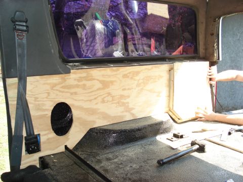 1992 Ford C-350 (Centurion Conversions) - Custom woodworking is being installed in the rear interior of a vehicle, with a speaker hole visible in the paneling.