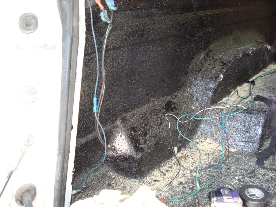 Inside of a vehicle, showing exposed wiring and sound deadening material on the floor and walls