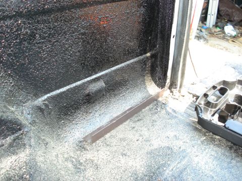 1992 Ford C-350 (Centurion Conversions) - Close-up view of the textured black interior of a wheel well, showing metal bracing and some debris.