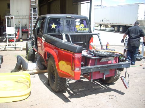 1992 Ford Ranger - Mechanic works on the rear of a 1992 Ford Ranger pickup truck in a garage setting.