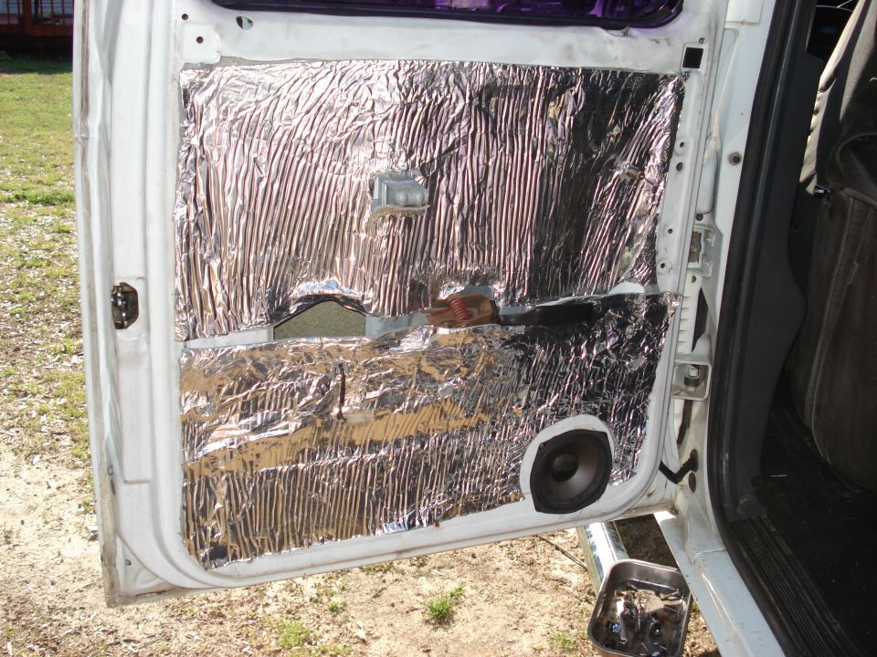Vehicle door panel removed, showing sound deadening material and a speaker installed