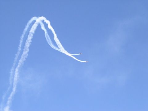 1979 Ford Bronco - Two planes create smoke trails while performing aerobatic maneuvers against a clear blue sky.