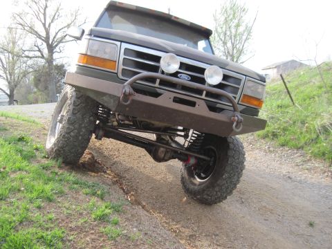 1995 Ford Bronco - This modified Ford Bronco is shown from a low front three-quarter angle on a dirt path.