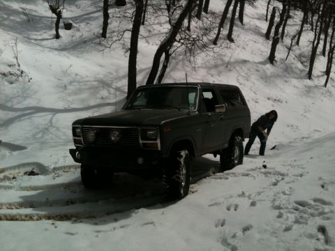 1982 Ford Bronco - Ford Bronco stuck in snow with a person attempting to dig it out.