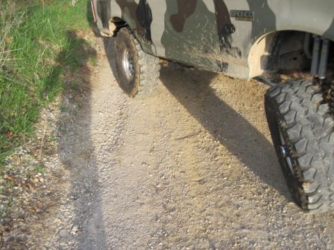 1995 Ford Bronco - A Ford Bronco with camouflage paint is driving on a gravel road.