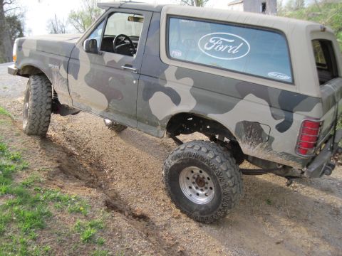 1995 Ford Bronco - This 1995 Ford Bronco, painted in camouflage, navigates a dirt path, its off-road capabilities.