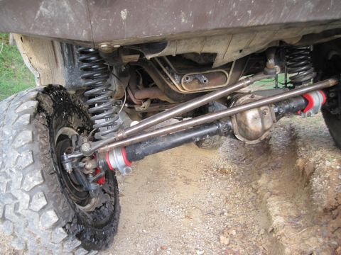 1995 Ford Bronco - The underside of a modified off-road vehicle shows heavy-duty steering and suspension components, including a Dana 44 axle.