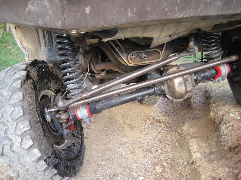 close-up of a lifted 4x4's front axle, steering linkage, and suspension with large off-road tires