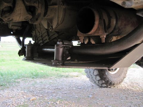 1995 Ford Bronco - Close-up of vehicle undercarriage components, including exhaust and crossmember, with a tire visible.