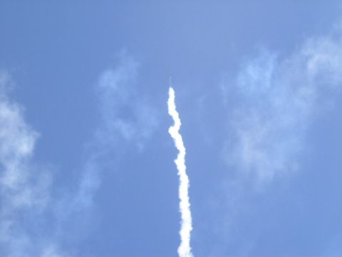 1979 Ford Bronco - A rocket ascends, leaving a white smoke trail against a bright blue sky.
