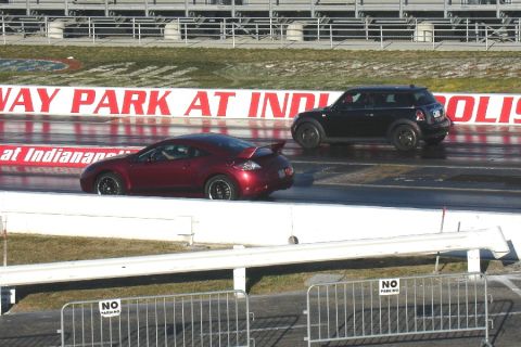 2010 MINI Cooper - Two cars compete on a drag strip with "WAY PARK AT INDIANAPOLIS" visible in the background.