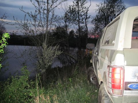 1995 Ford Bronco - Ford Bronco parked near water at dusk, showing its rear quarter panel and camouflage paint.