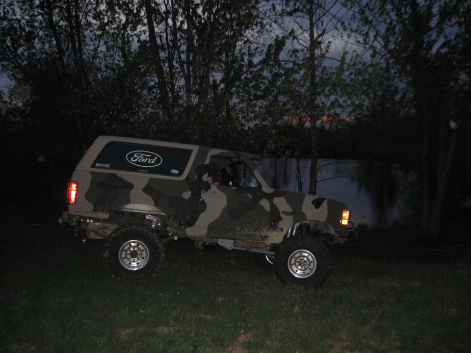 Ford Bronco with camouflage paint job parked on grass at dusk