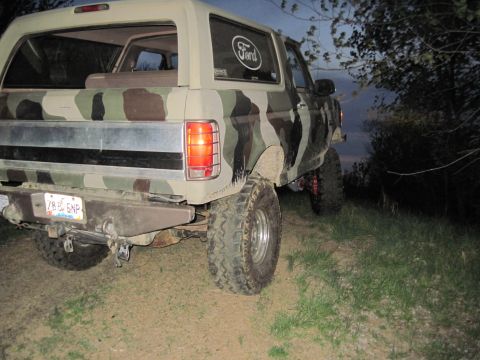 1995 Ford Bronco - Camouflaged 1995 Ford Bronco parked off-road at dusk.